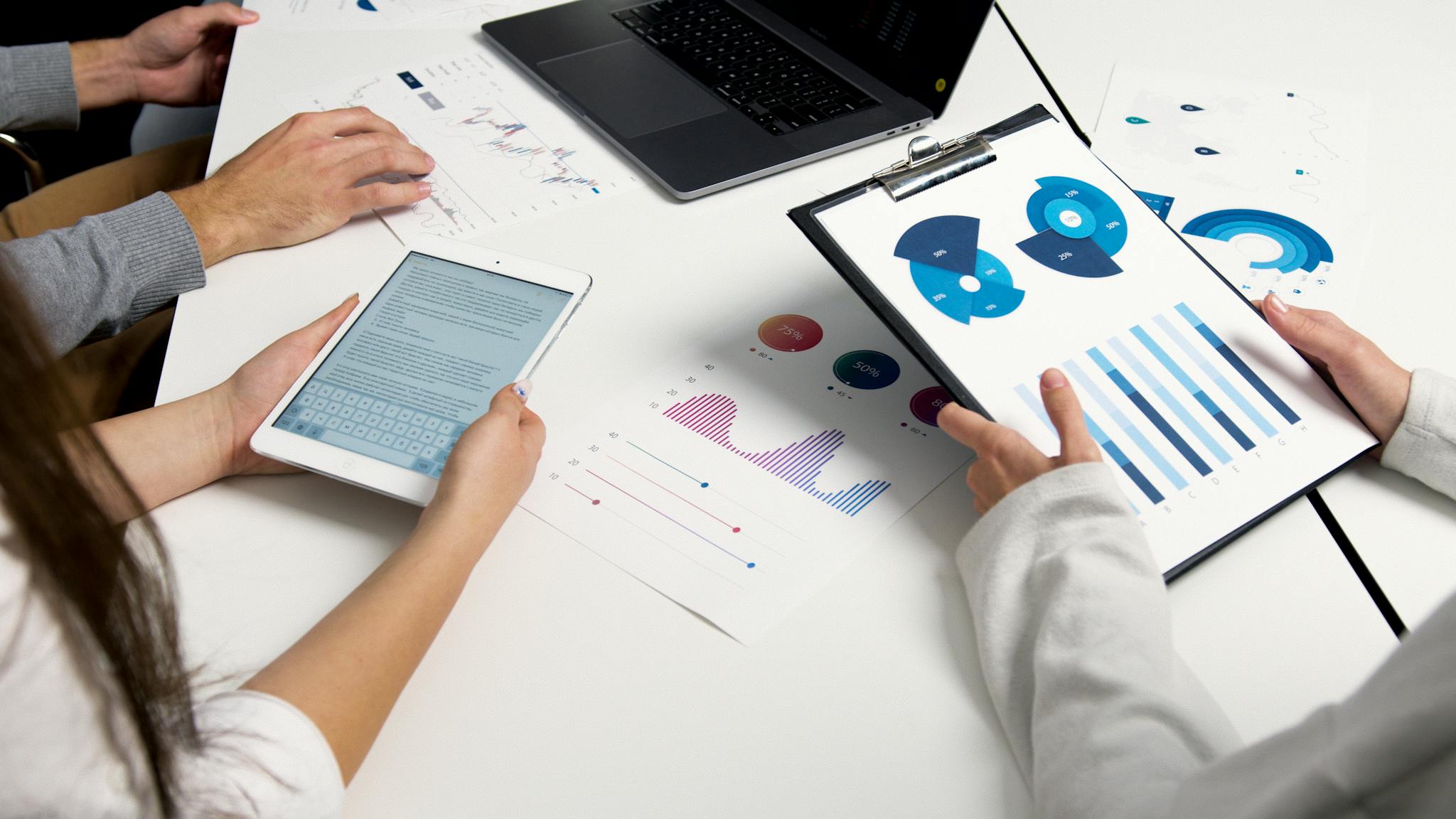 Team analyzing financial charts and digital reports during a business meeting.