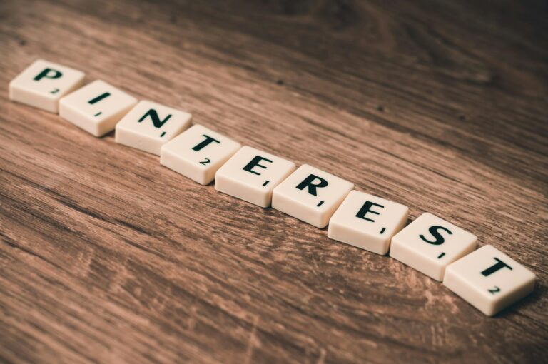 Wooden letter tiles arranged to spell Pinterest on a wooden table, ideal for social media themes.